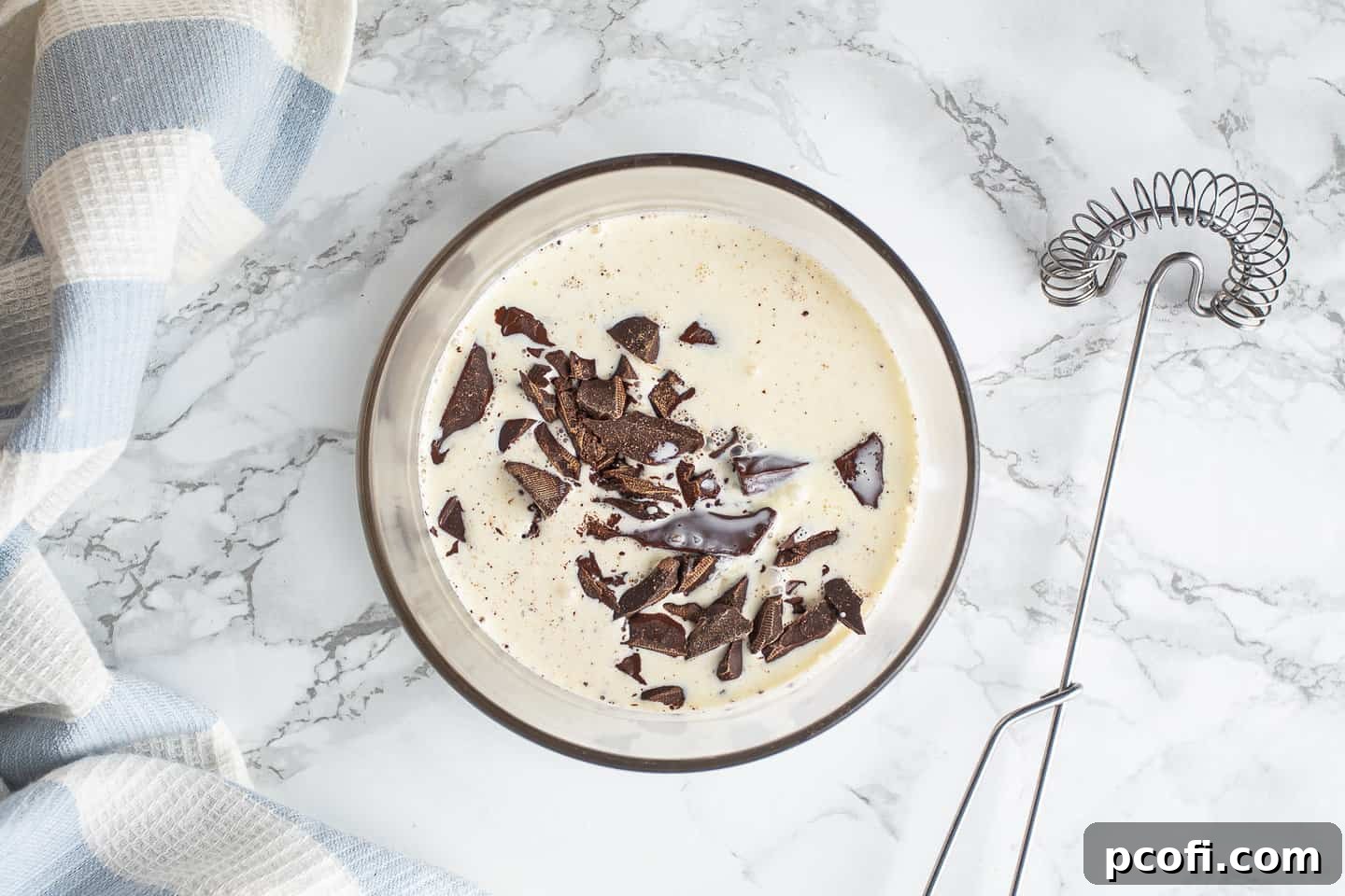 Hot cream and chopped chocolate in a glass bowl.
