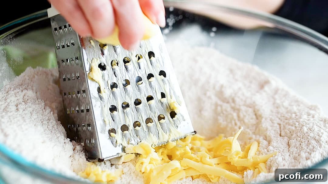 Grating very cold butter into the bowl of dry ingredients for scones.
