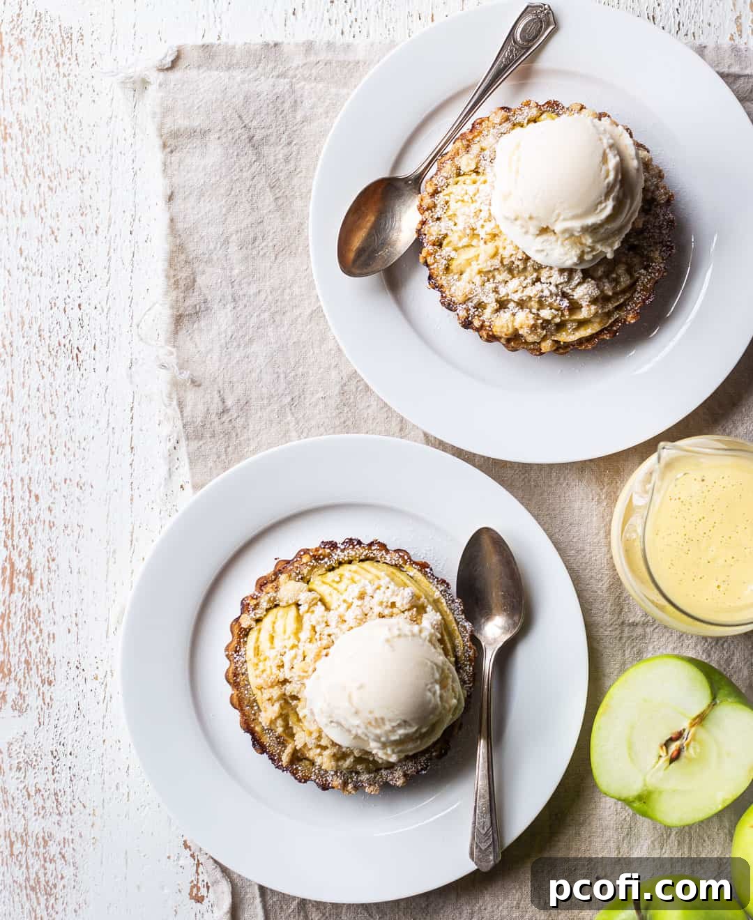 Overhead image of individual apple tarts, artfully served with melting vanilla ice cream and a luscious pour of custard sauce.
