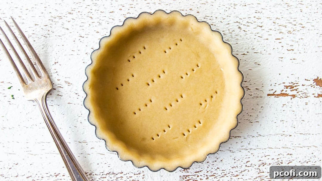 Docking mini tart dough with a fork to allow air to escape during baking.