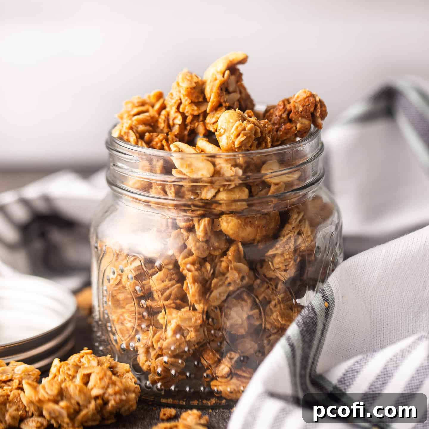 Hearty peanut butter granola beautifully presented in a glass jar, accompanied by a charming plaid cloth.