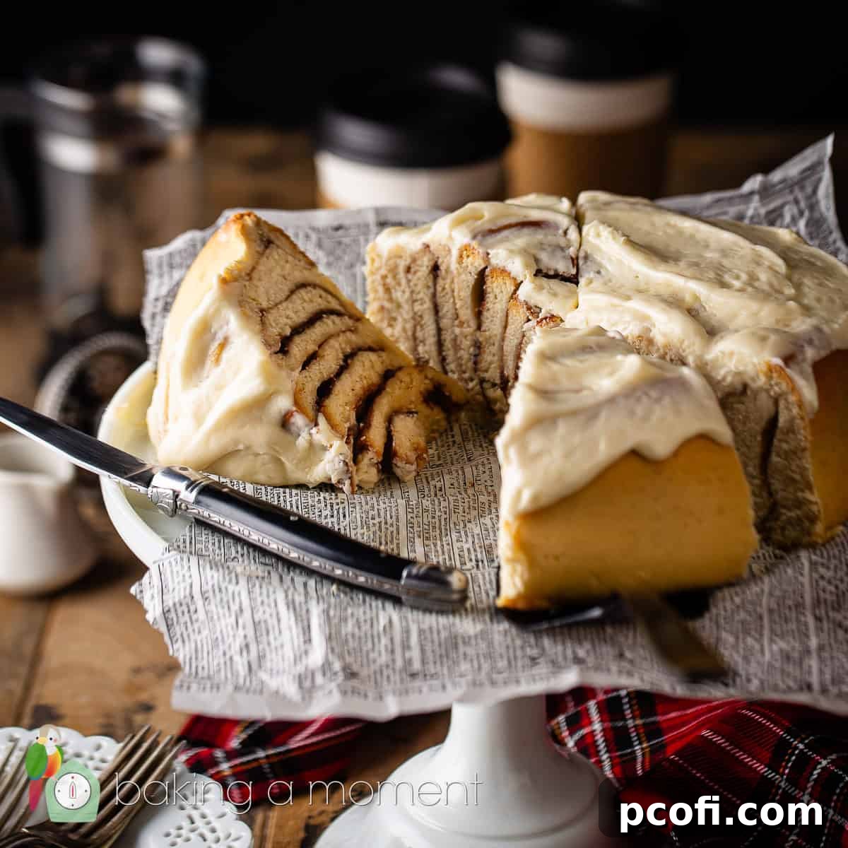 A generous slice of a cinnamon roll cake, beautifully presented on a cake stand, showcasing its swirled interior and creamy frosting.