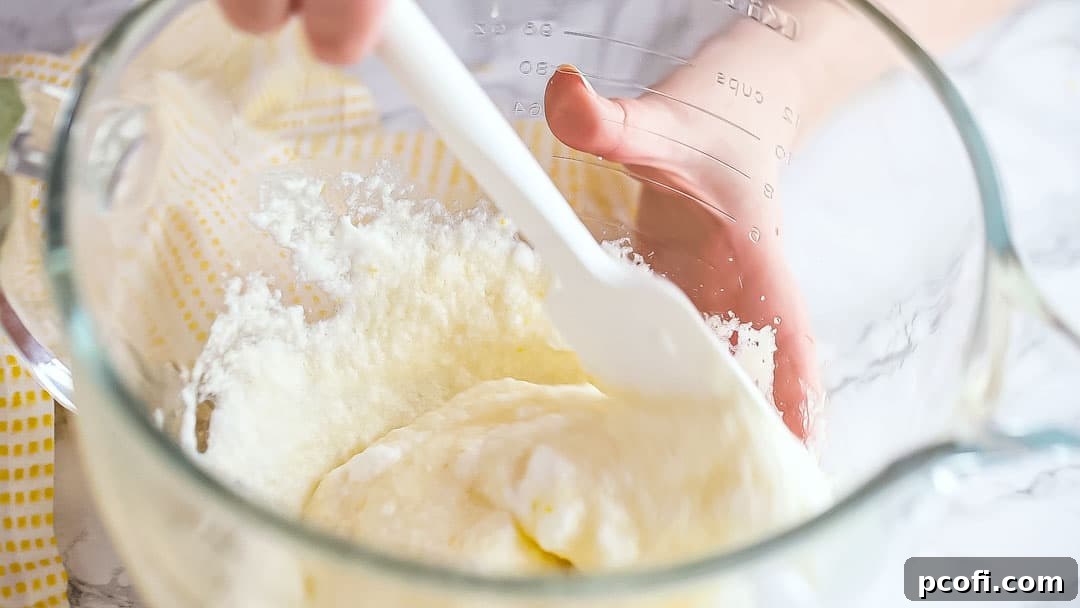 Gently folding the lemon pudding cake batter to preserve airiness.