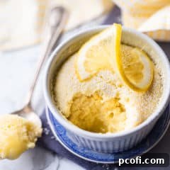 Lemon pudding cake in a ramekin with a lemon twist on top.
