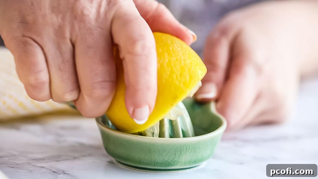 Juicing half a lemon with a small ceramic juicer into a bowl.