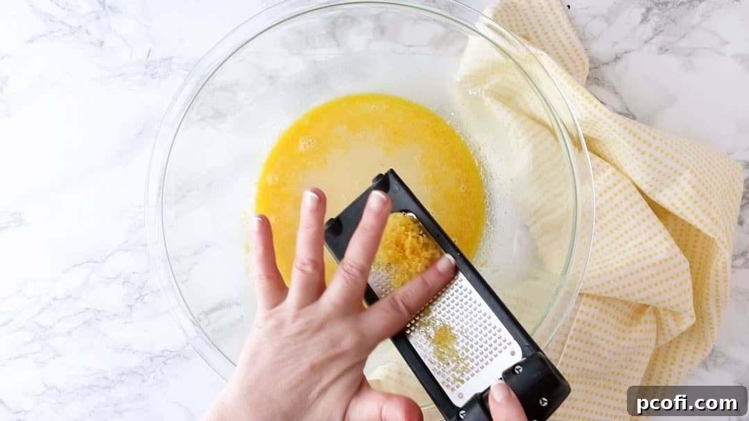Zesting a lemon with a microplane over a mixing bowl.