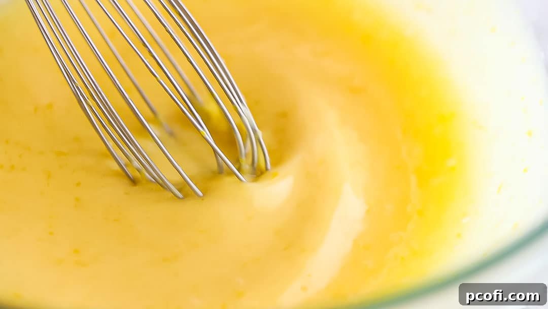 Whisking the lemon pudding cake batter until uniformly smooth and fragrant.