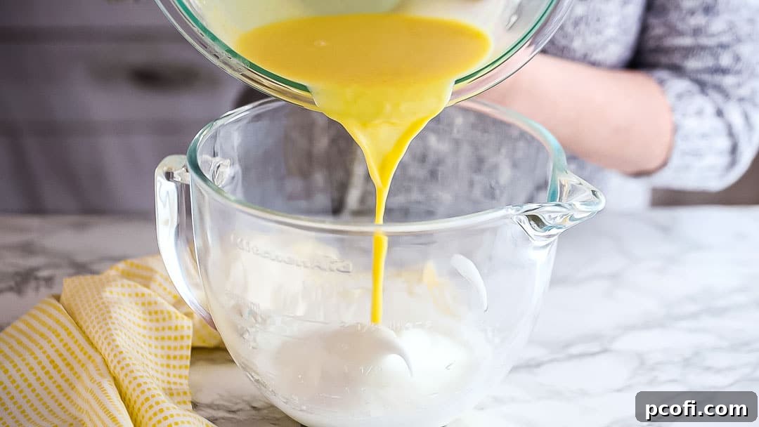 Adding a portion of the lemon mixture to stiffly whipped egg whites.