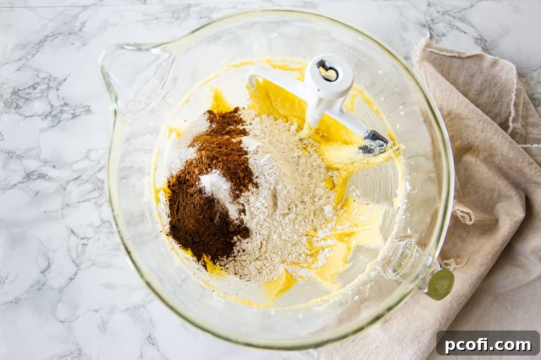 Adding dry ingredients to chocolate pound cake batter.
