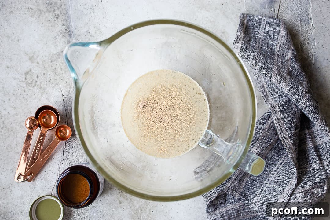 Dissolving active dry yeast in cool water and honey mixture in a glass bowl.