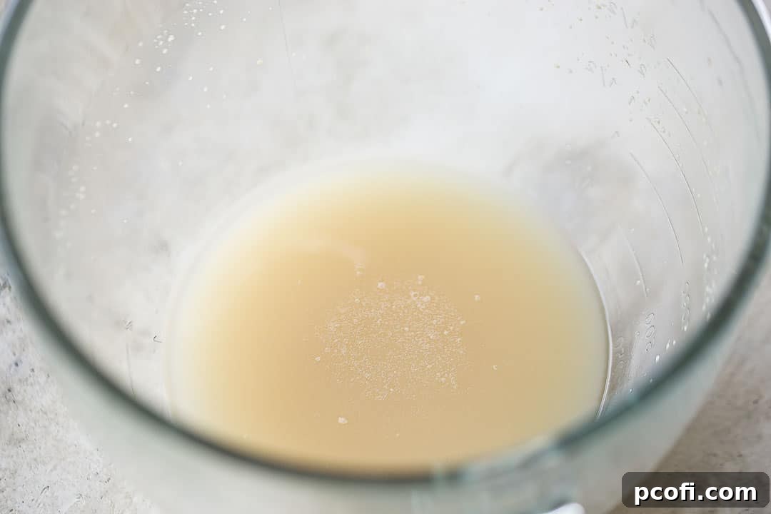 Foaming dissolved yeast mixture, indicating active yeast, in a glass mixing bowl.