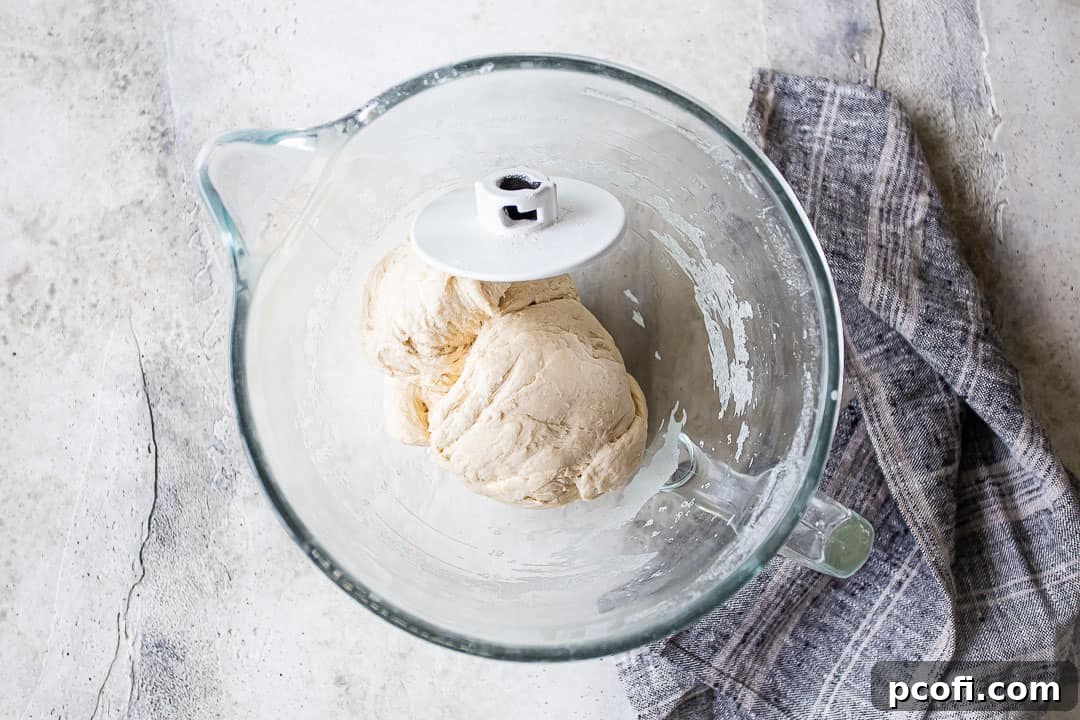 Smooth, elastic bagel dough resting in a mixing bowl with a dough hook.