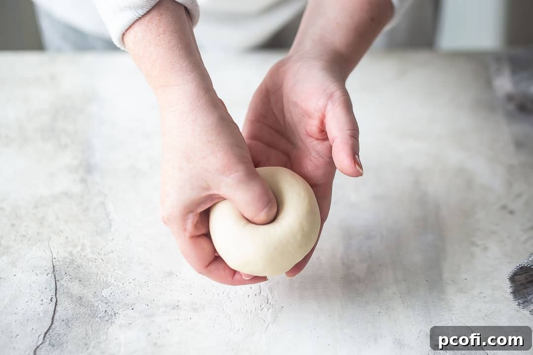 Demonstration of how to create the center hole in a homemade bagel using a thumb.