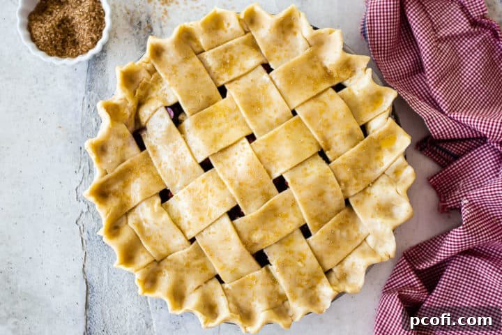 An unbaked cherry pie, beautifully crimped and sprinkled with coarse sugar, ready for the oven to transform it into a golden masterpiece.
