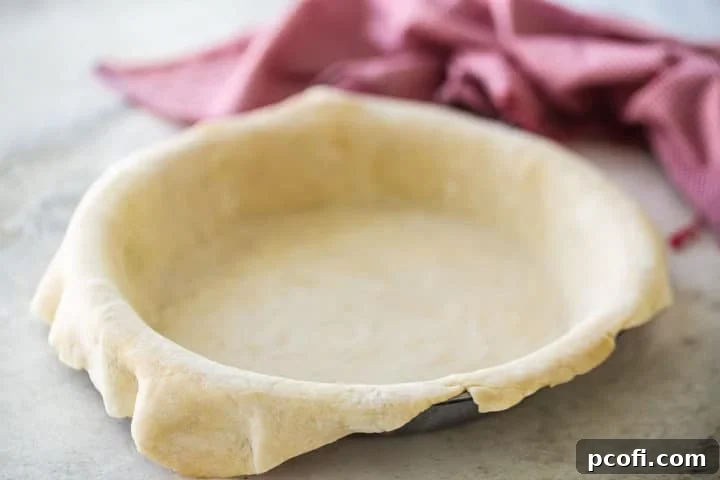 Unbaked pie crust, expertly made, rolled out, and gently draped into a pie dish, ready for the delicious cherry filling.
