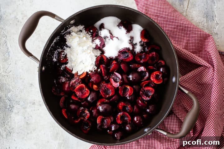 Halved, pitted cherries in a large pot, mixed with sugar, cornstarch, lemon juice, and a pinch of salt, ready to be cooked into a rich pie filling.