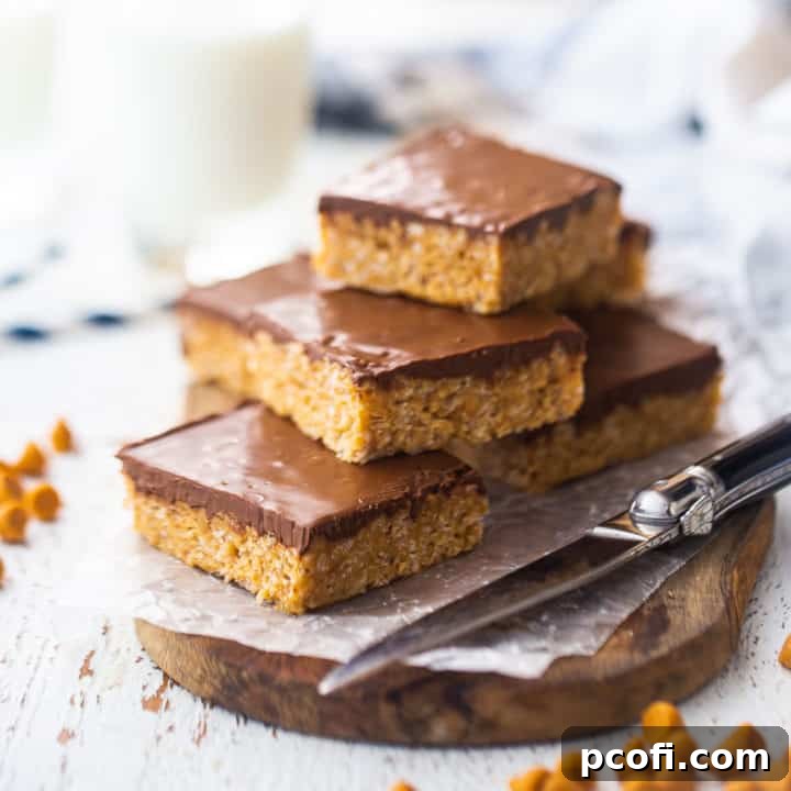 Scotcheroos stacked on a wooden serving board, showcasing the peanut butter rice krispie base and the chocolate butterscotch topping.