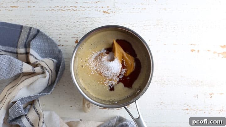 Adding peanut butter and salt to hot honey mixture, ensuring smooth incorporation.