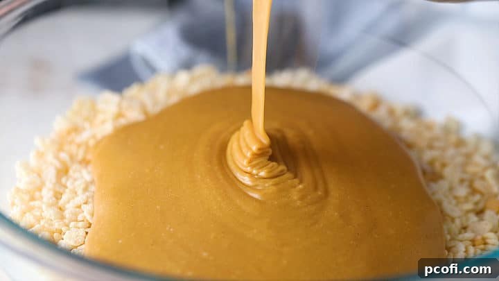 Pouring peanut butter mixture over rice krispies to make scotcheroos recipe, ensuring even distribution.