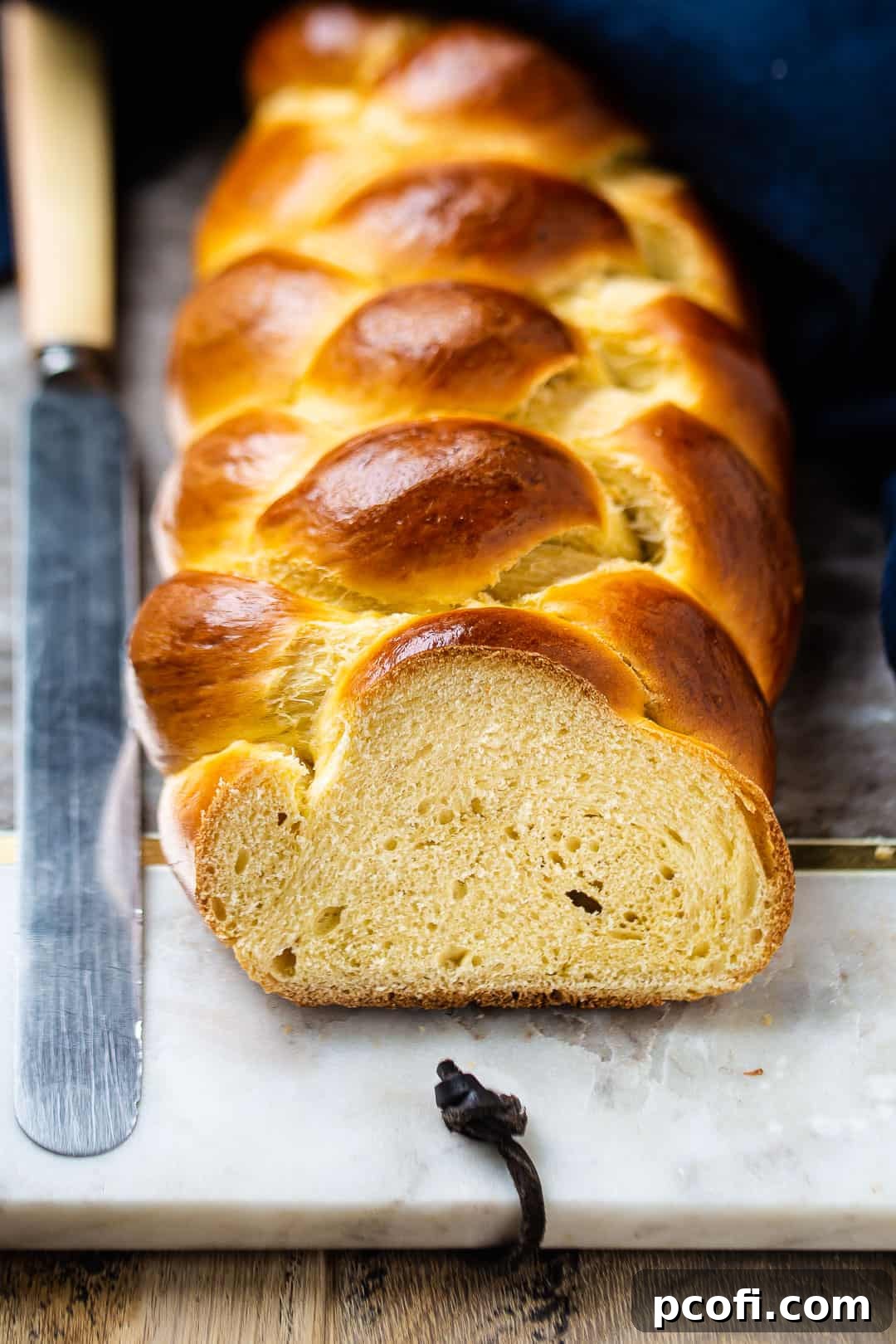 Challah recipe baked in a long braid and sliced, showing the fluffy inside of the bread.