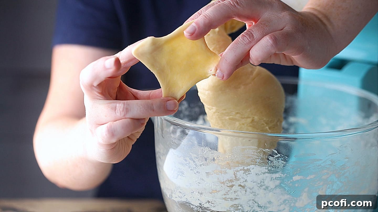 Performing the windowpane test on challah dough.