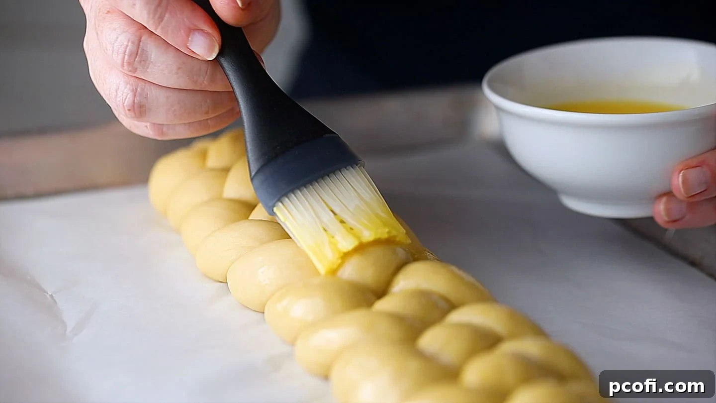Brushing unbaked challah with egg wash.