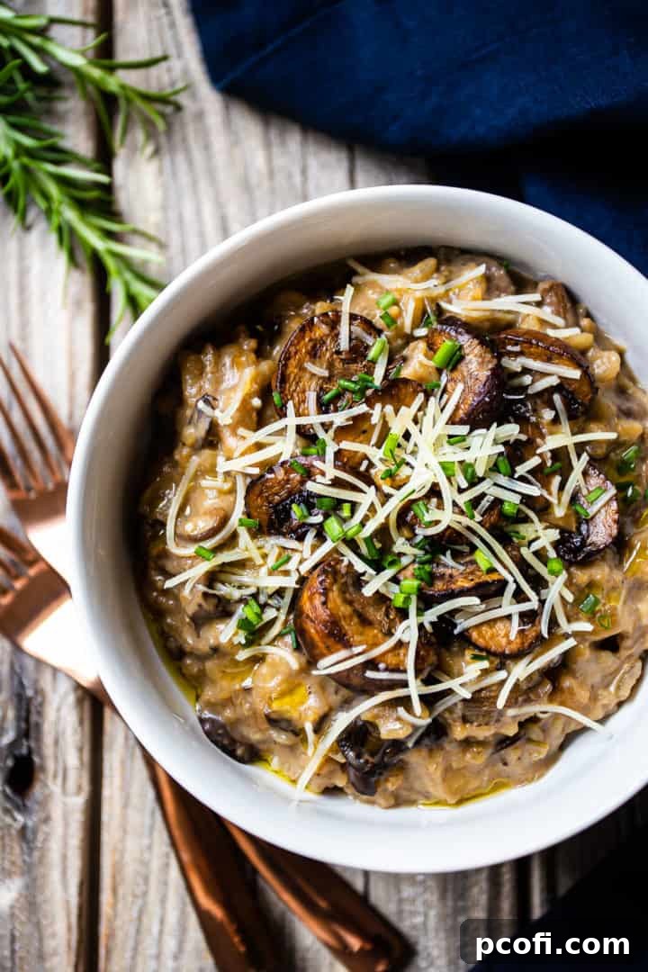 Overhead image of a bowl of vegan mushroom risotto on a rustic wooden background, with a blue linen napkin and copper fork.