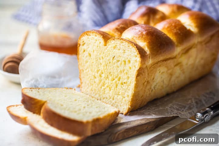 Brioche bread loaf sliced, with a jar of honey in the background.
