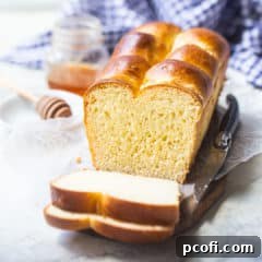 Brioche loaf on a wooden board with a blue checked cloth in the background.