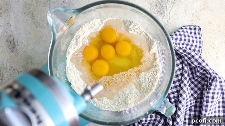 Adding water, yeast, sugar, salt, and eggs to flour.