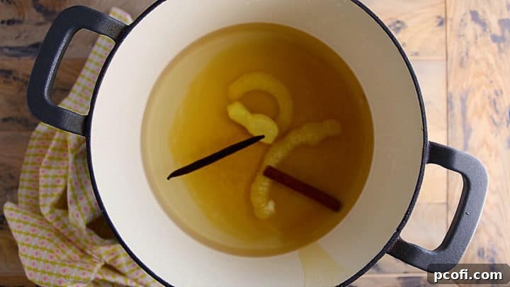 Overhead view of the aromatic poaching liquid simmering in a large pot, with ingredients like wine, honey, and spices visible.