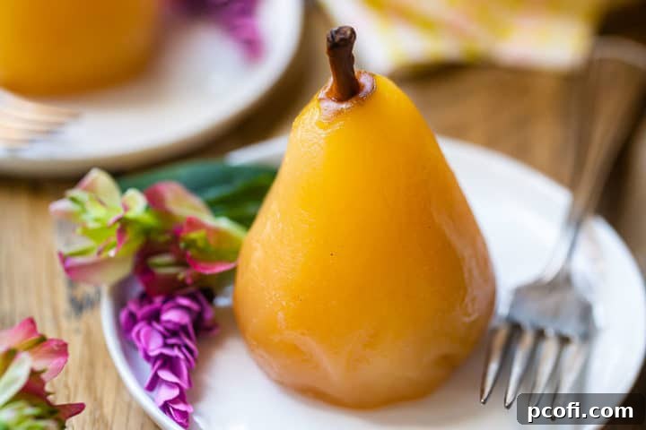 A single poached pear on a plate, garnished with a vintage silver fork and delicate pink flowers.