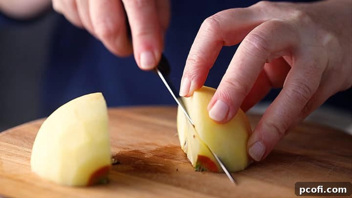 Cutting the core out of a quartered apple, a key step for preparing fruit for homemade applesauce.