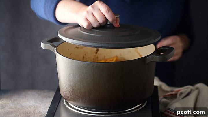 Covering a pot of homemade applesauce with a tight fitting lid to begin simmering.