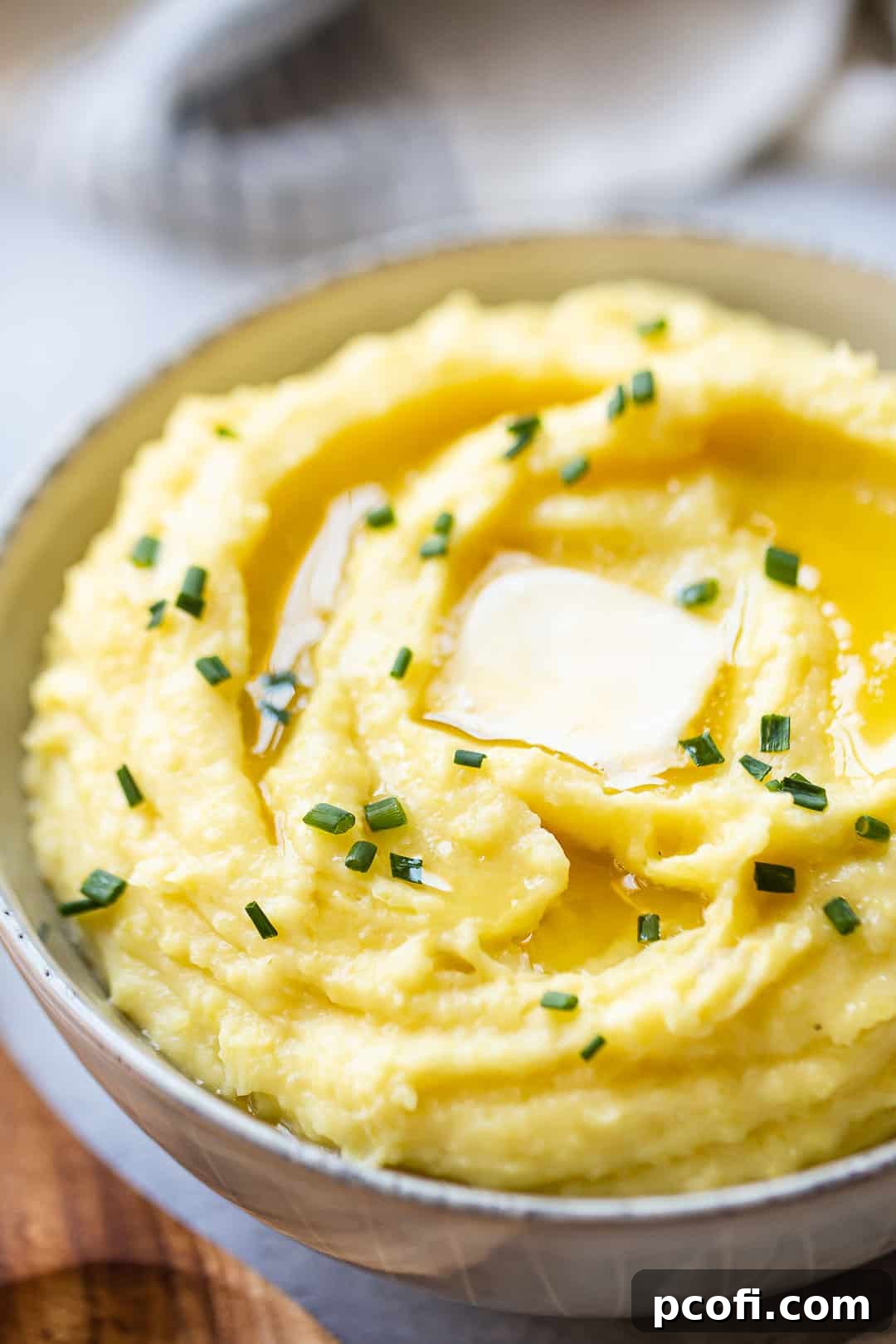 Close-up image of a bowl of creamy mashed potatoes garnished with fresh chives, ready to serve.