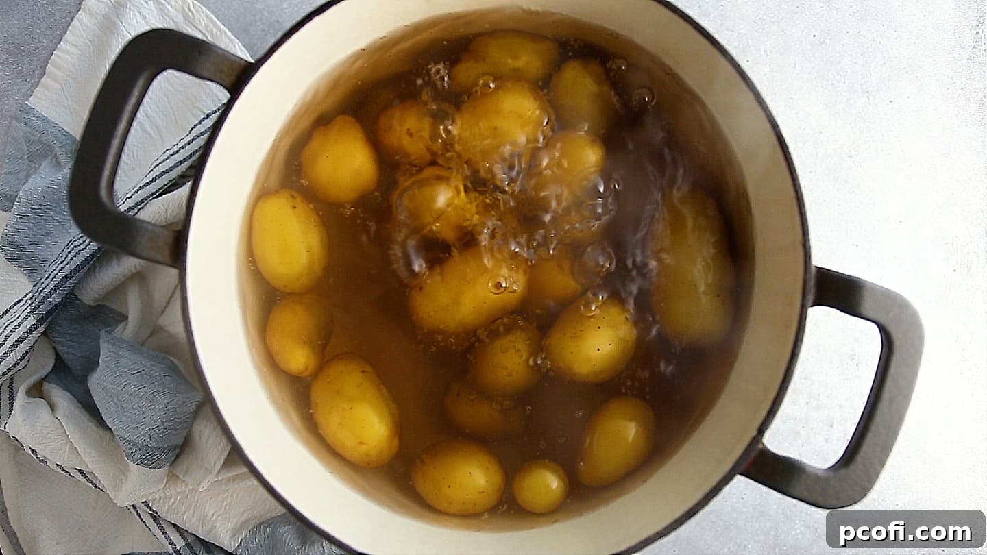 Whole potatoes simmering gently in a large pot of salted water on the stovetop.