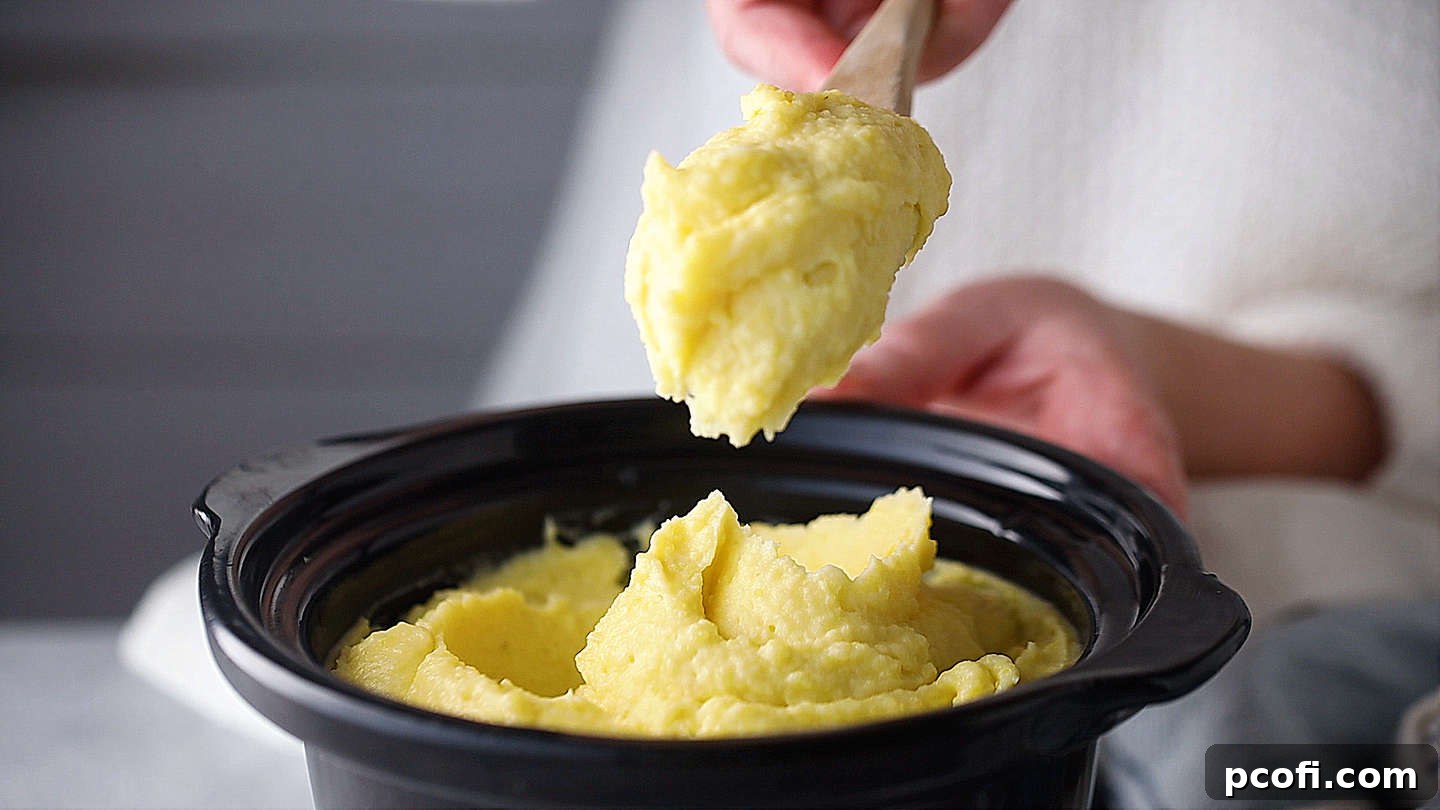 Scooping perfectly smooth and fluffy make-ahead mashed potatoes from a slow cooker.