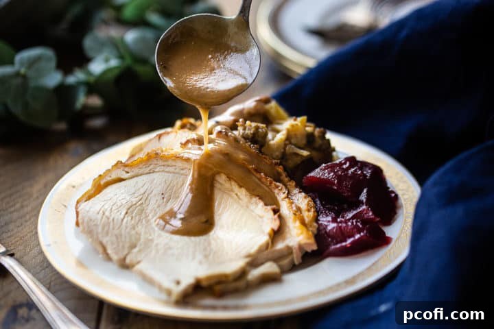 Ladling rich brown turkey gravy over thinly sliced roasted turkey and flavorful stuffing on a plate.