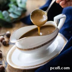 Ladling brown gravy from a bone china gravy boat.