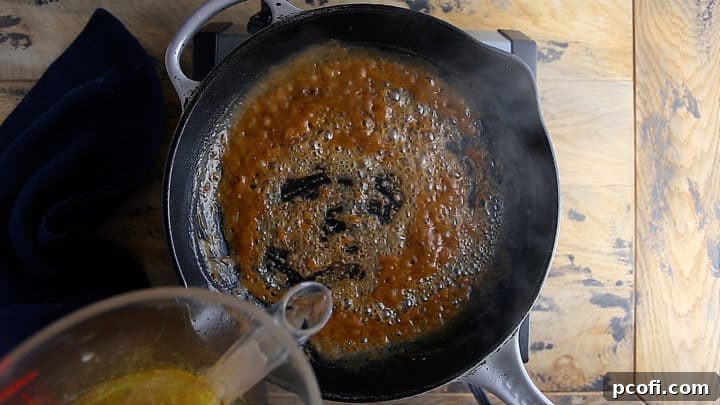 Pouring rich pan juices into a browned roux, stirring to combine.
