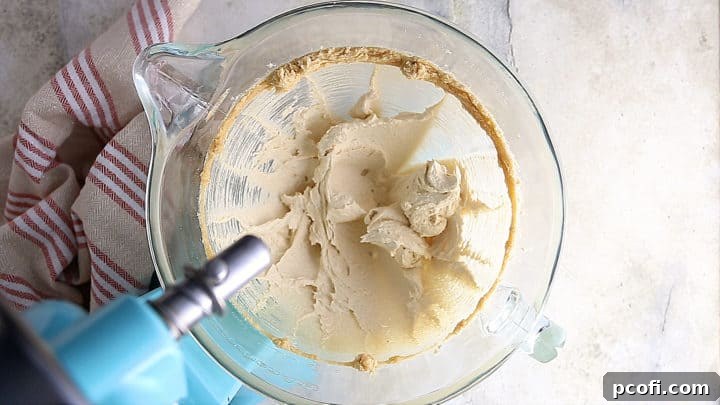 Softened butter and a mixture of brown and white sugars being creamed together in a mixing bowl until light and fluffy.