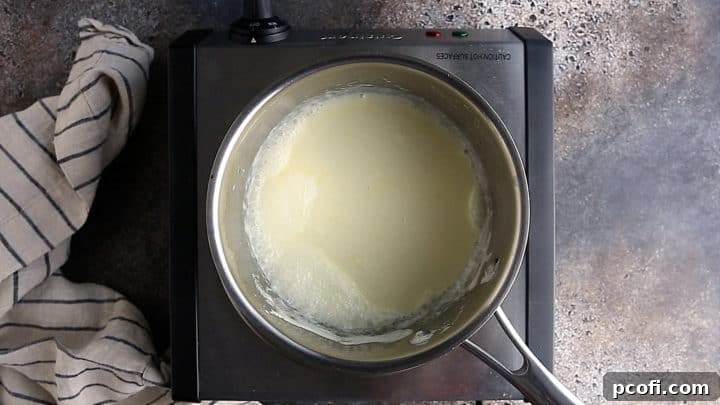 Hot cream in a small stainless steel pot.