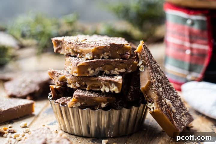 Beautifully stacked shards of homemade toffee in a gleaming metal dish, set against a festive background of ribbons and greenery, perfect for gifting or serving.