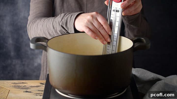 A candy thermometer being securely clipped to the side of the pot, essential for accurate temperature monitoring during toffee making.