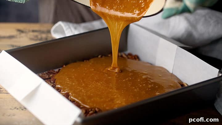 Carefully pouring the extremely hot, freshly made toffee mixture over a layer of toasted nuts in the prepared baking pan.