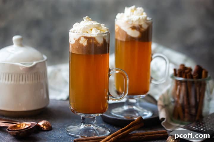 Several mugs of hot buttered rum, topped with whipped cream and a sprinkle of nutmeg, arranged on a cozy, festive backdrop.