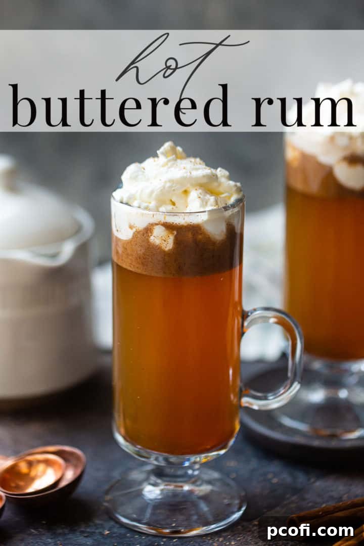 Two mugs of hot buttered rum, freshly prepared and topped with a generous swirl of whipped cream and a sprinkle of nutmeg, presented on a rustic wooden surface.