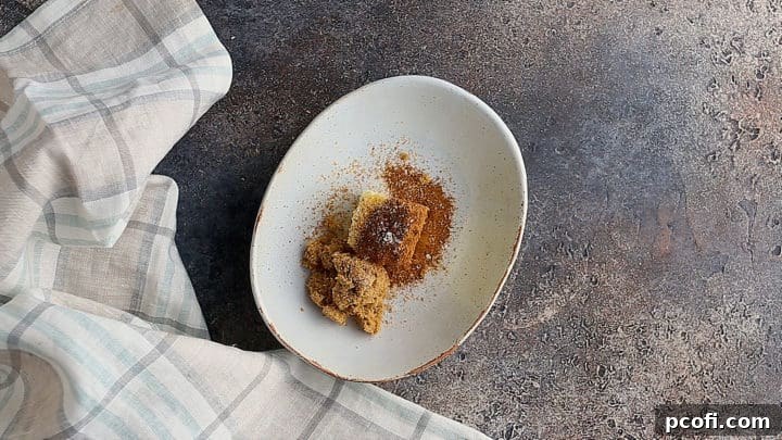 Key ingredients for hot buttered rum batter: softened unsalted butter, dark brown sugar, ground cinnamon, nutmeg, and cloves, arranged on a rustic ceramic dish.
