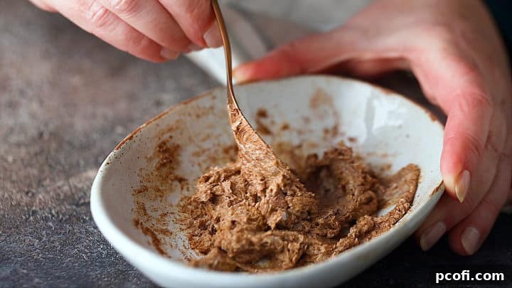 Close-up of the hot buttered rum batter being mixed in a bowl, showcasing the rich, brown sugar and spice blend forming a smooth paste.