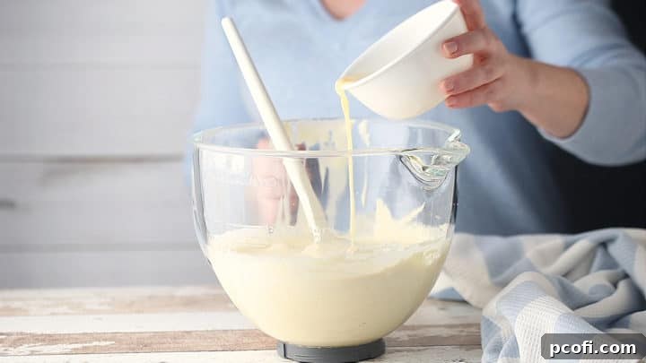 Adding melted butter to the delicate batter, taking care to fold it in thoroughly without deflating the mixture.